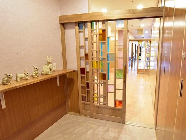 ステンドグラス風のガラス戸が付いたエントランス周辺。猫の置物がたくさん置かれ、通行の邪魔となるようなものはない。