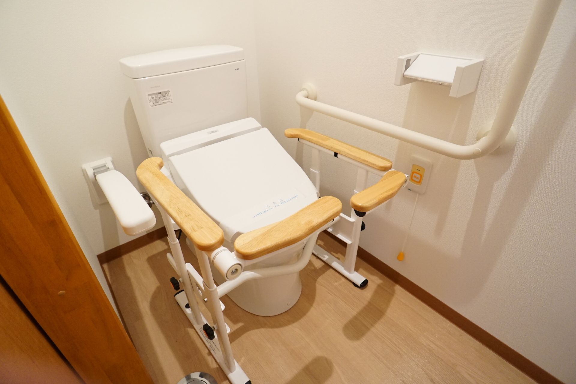 L字の手すりが付いた白い部屋にある車いす対応トイレ