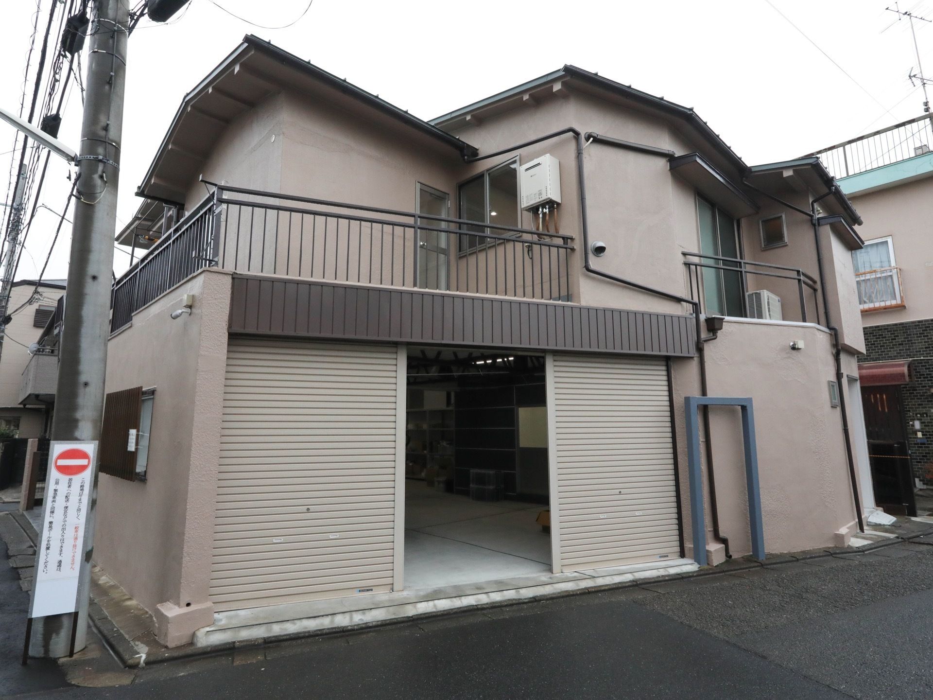 一軒屋のような外観で、１階はシャッターの付いた駐車場である。２階にはベランダがあり、柵で囲ってある。