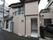 出入り口と道路までの間に、段差解消用品が置いてある。建物は角地にあり、隣接する道路に進入禁止のマークが記された看板が立てられている。