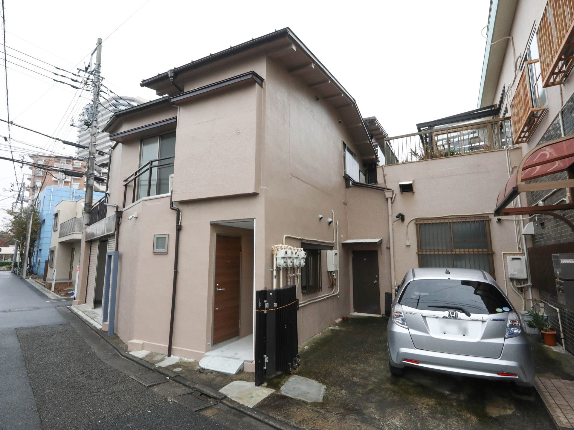 施設の外壁は茶色い色味で、２階建ての建物となっている。玄関には、シルバーの取っ手がついた木目調の扉が取りつけられている。