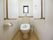 トイレの両側の壁に大きなL字型の手すりが取り付けられている。便器のふたと正面の棚の上に車椅子のマークが描かれた紙が貼られている。