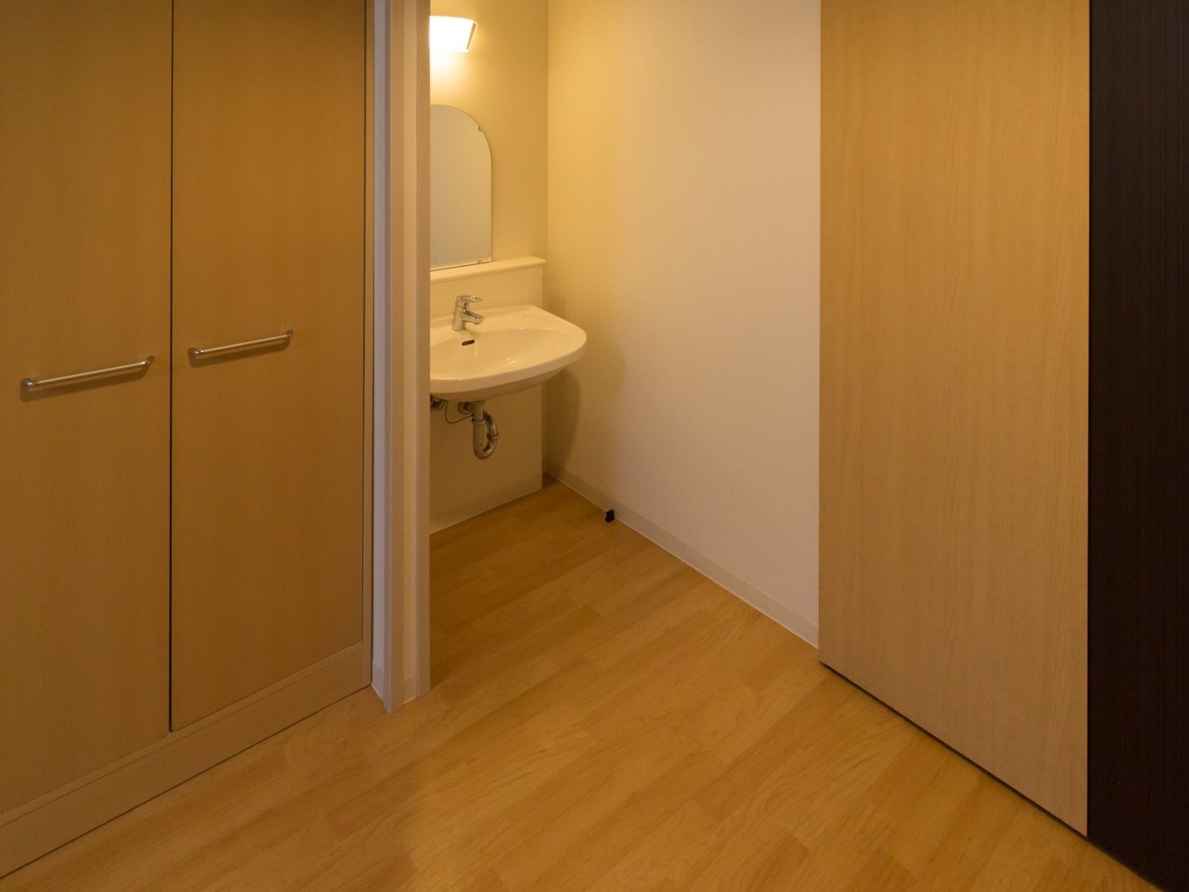 部屋の扉を入るとすぐに、鏡付きの洗面台がある。足元は車椅子でも使いやすいよう、シンプルな配管のみになっている。