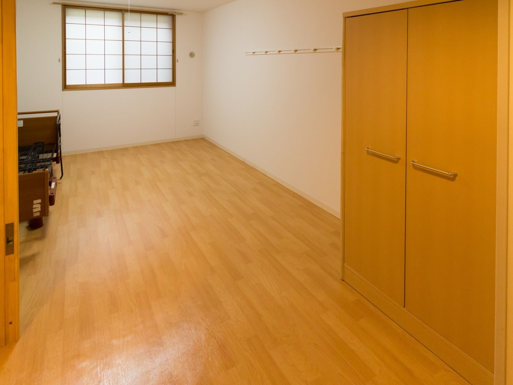 フローリングの部屋に、電動ベッドとクローゼットが置かれている。窓には障子がついていて、柔らかい明るさがある。