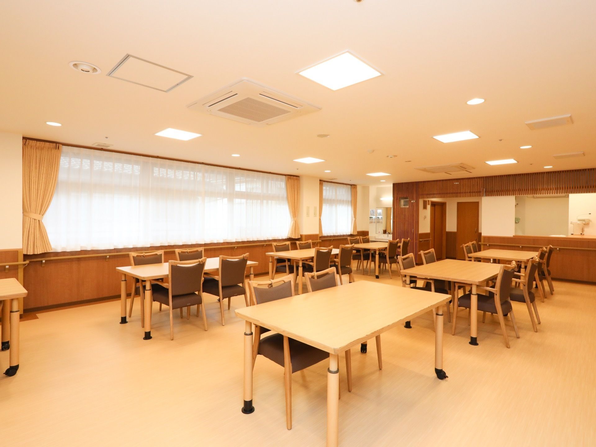 あたたかい光がたっぷりと差し込むダイニング。ブラウンを基調とした家具が複数組セッティングされている。