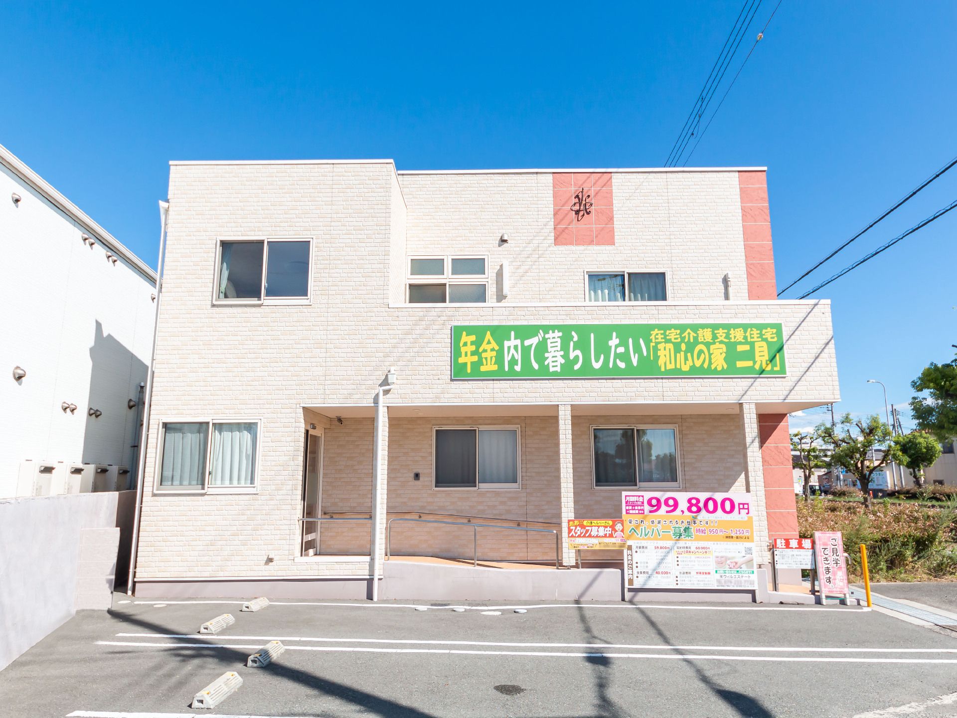 アスファルトに隣接している白い外観で２階建ての建物