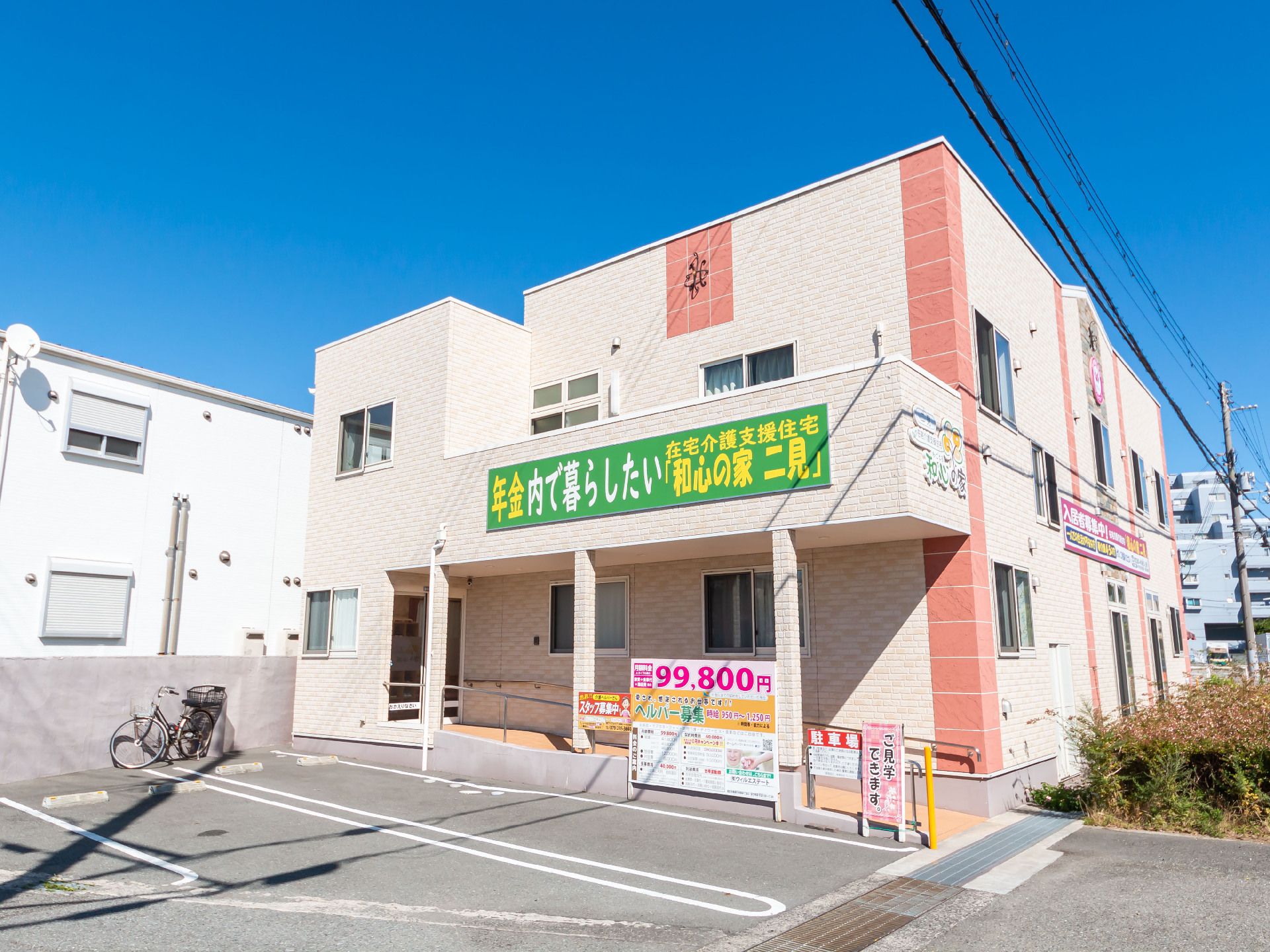 アスファルトに隣接している白い外観で２階建ての建物