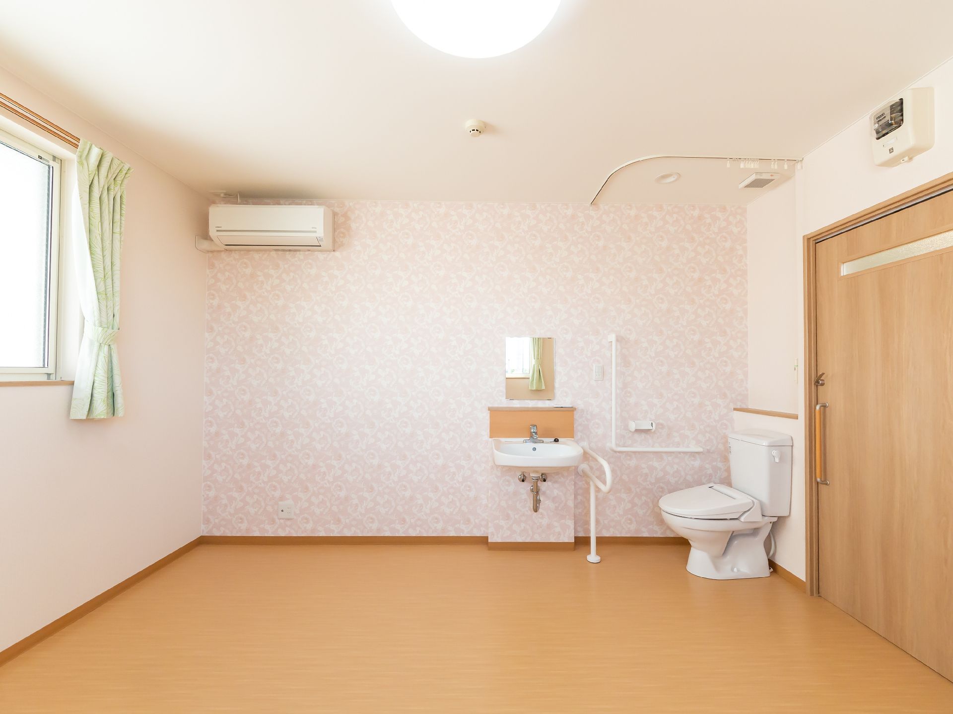 壁際に洗面台と洋式便器が並んでいる白い壁の部屋