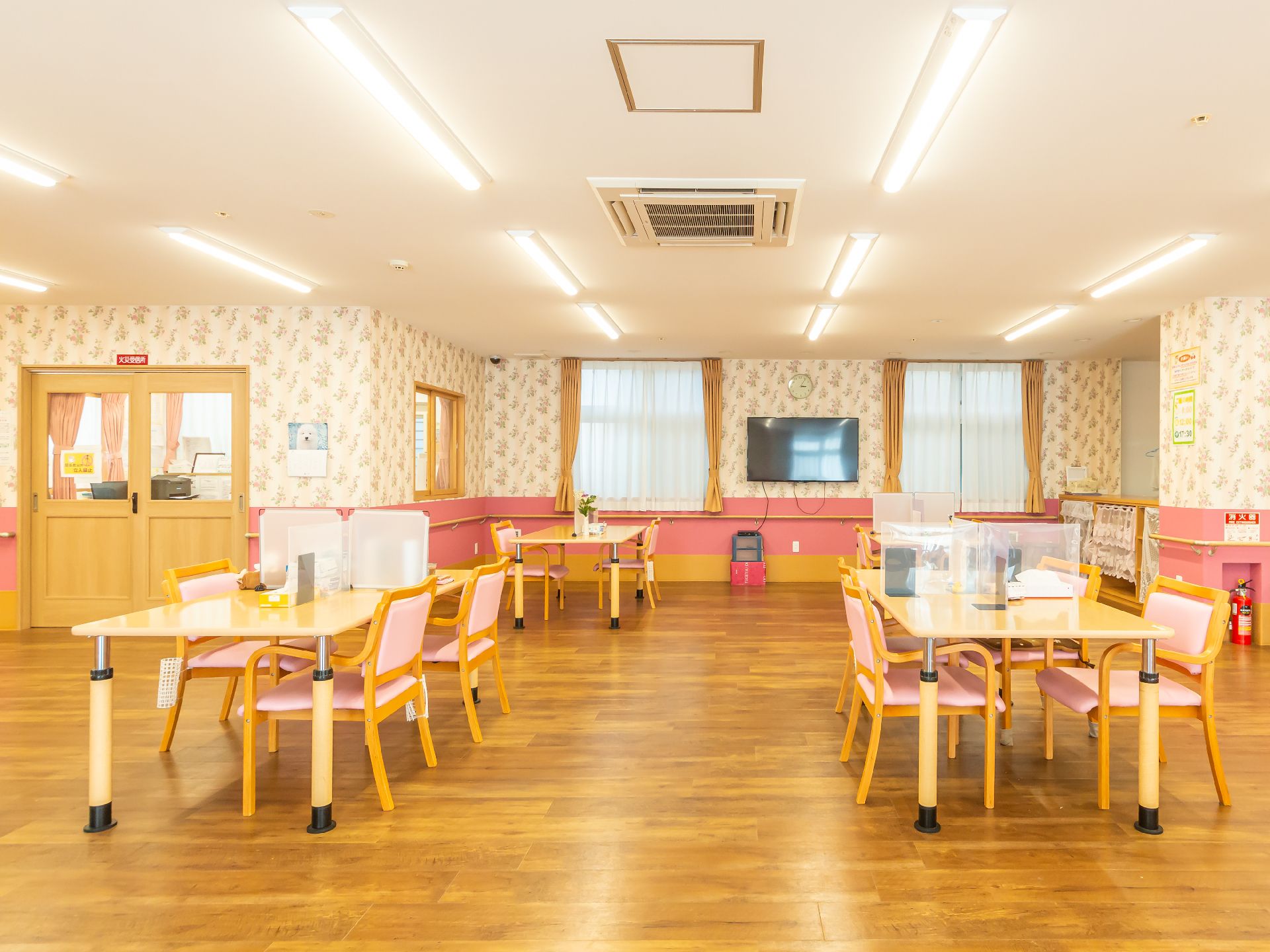 木製の机が並べられた白い壁の広間