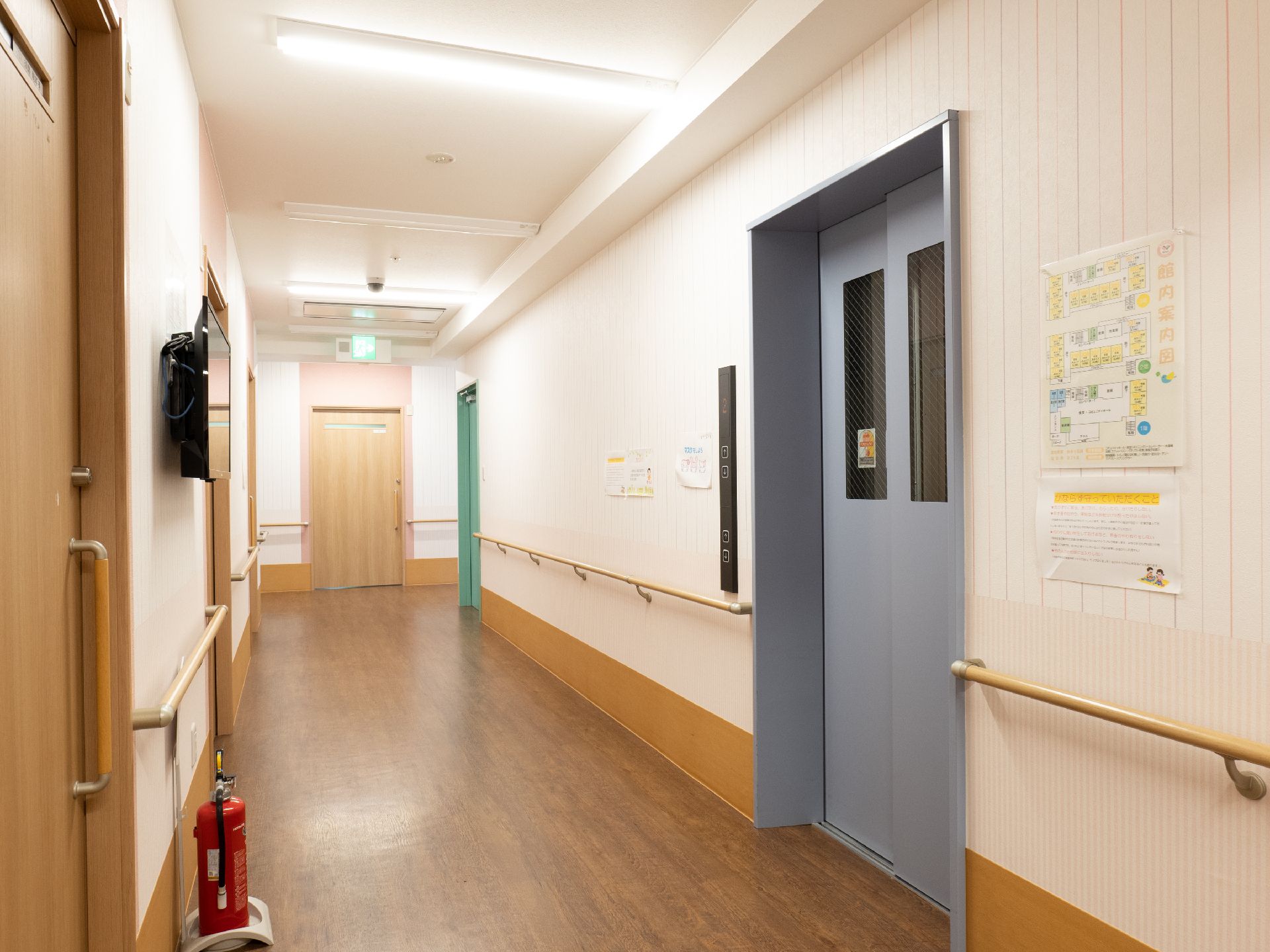 水の入ったコップを持った女性スタッフが薬を飲もうとしている高齢女性のそばで微笑んでいる。