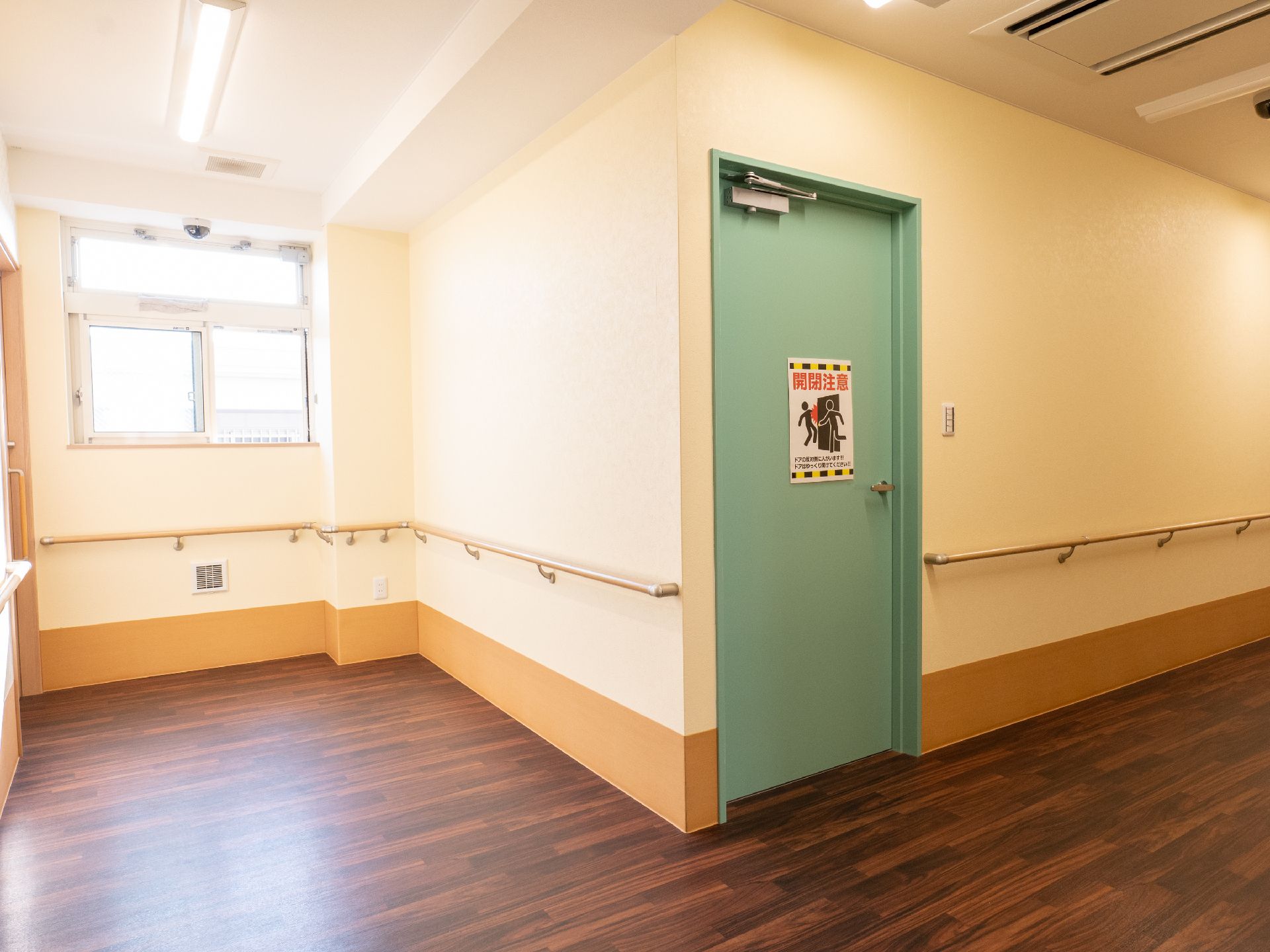 高齢者女性たちと白衣を着た女性スタッフが、ベージュのソファを囲んで楽しそうに話している。