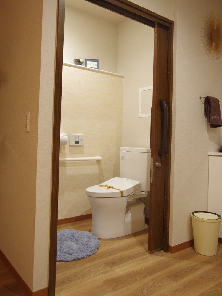 引き戸が付いた広いトイレには棚や手すりが付き、壁に操作パネルが付いている。