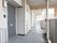 マンションの部屋が並んでいる。外廊下になっている。右側に手すりがあり、その途中に消火栓が設けられている。
