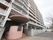 マンションの玄関となっている。高層の建物の１階にピンクベージュのスロープがあり、屋根が設けられている。