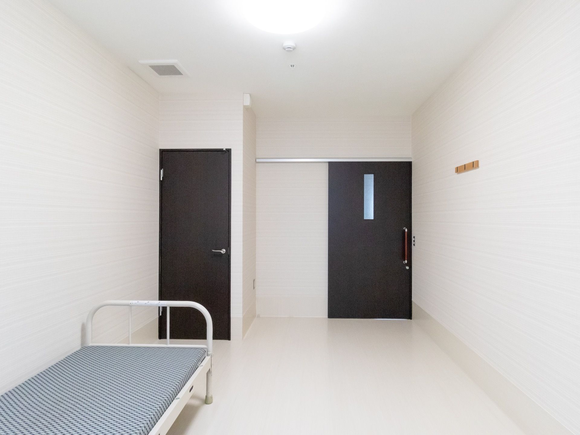 ベッドの設置された高齢者施設の居室。入り口は引き戸になっている。