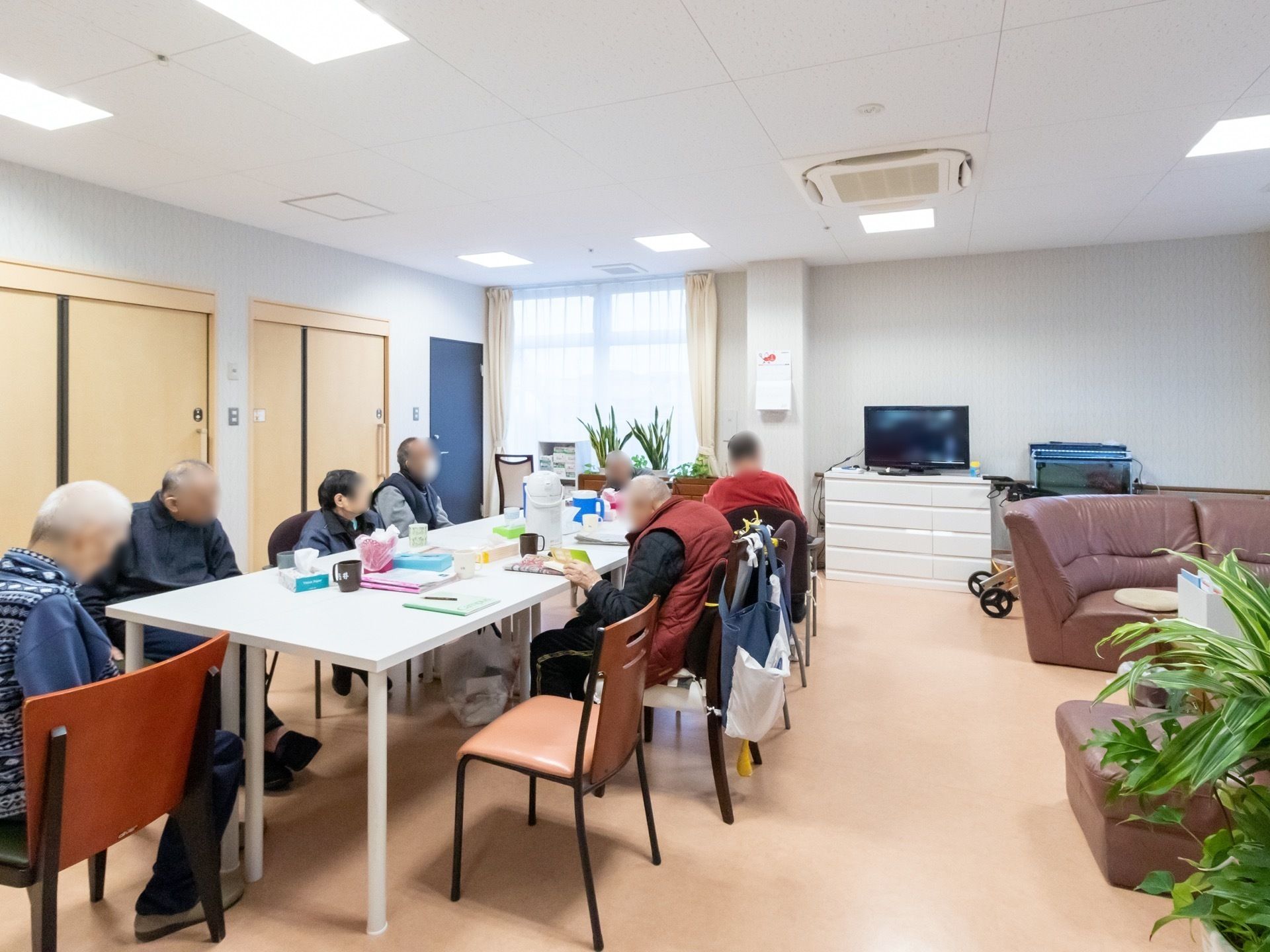 共有スペースに集まり、大きなテーブルを囲んで座る入居者たち