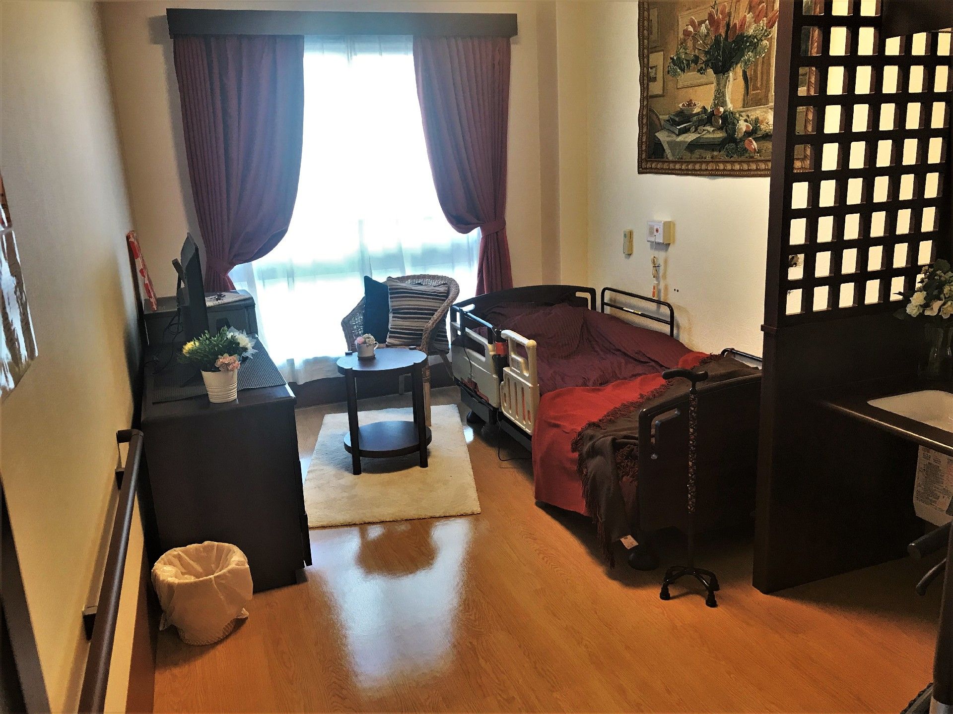 介護用ベッドとたんす、いす、小さなテーブルが置いてあるホスピス内の居室