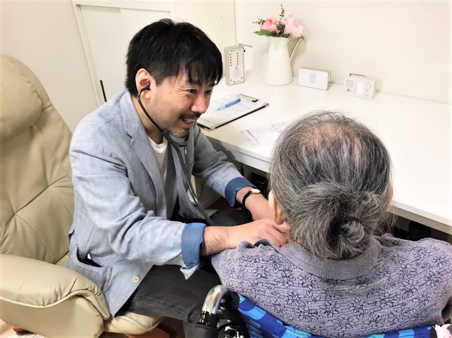 医師が高齢者の体を聴診器で診察している様子。施設内の活動の様子