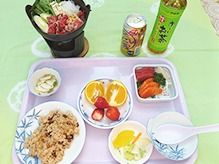 ごはんとおかず類、フルーツがお盆に並べられている施設の食事メニュー