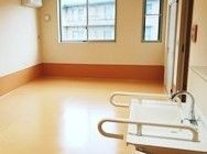 手前に手すり付きの洗面台がある広めのスペース。エアコンと窓がついた広めの部屋