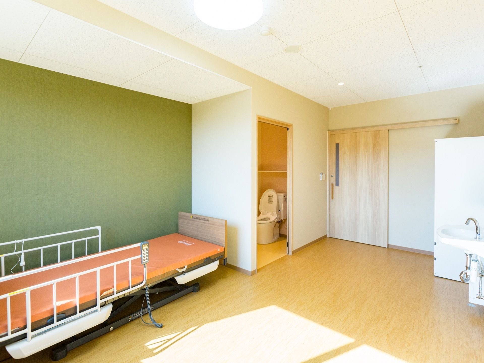 シンプルな個室である。介護用ベッドが用意されており、トイレの扉はスライドドアである。クローゼットが備え付けられている。