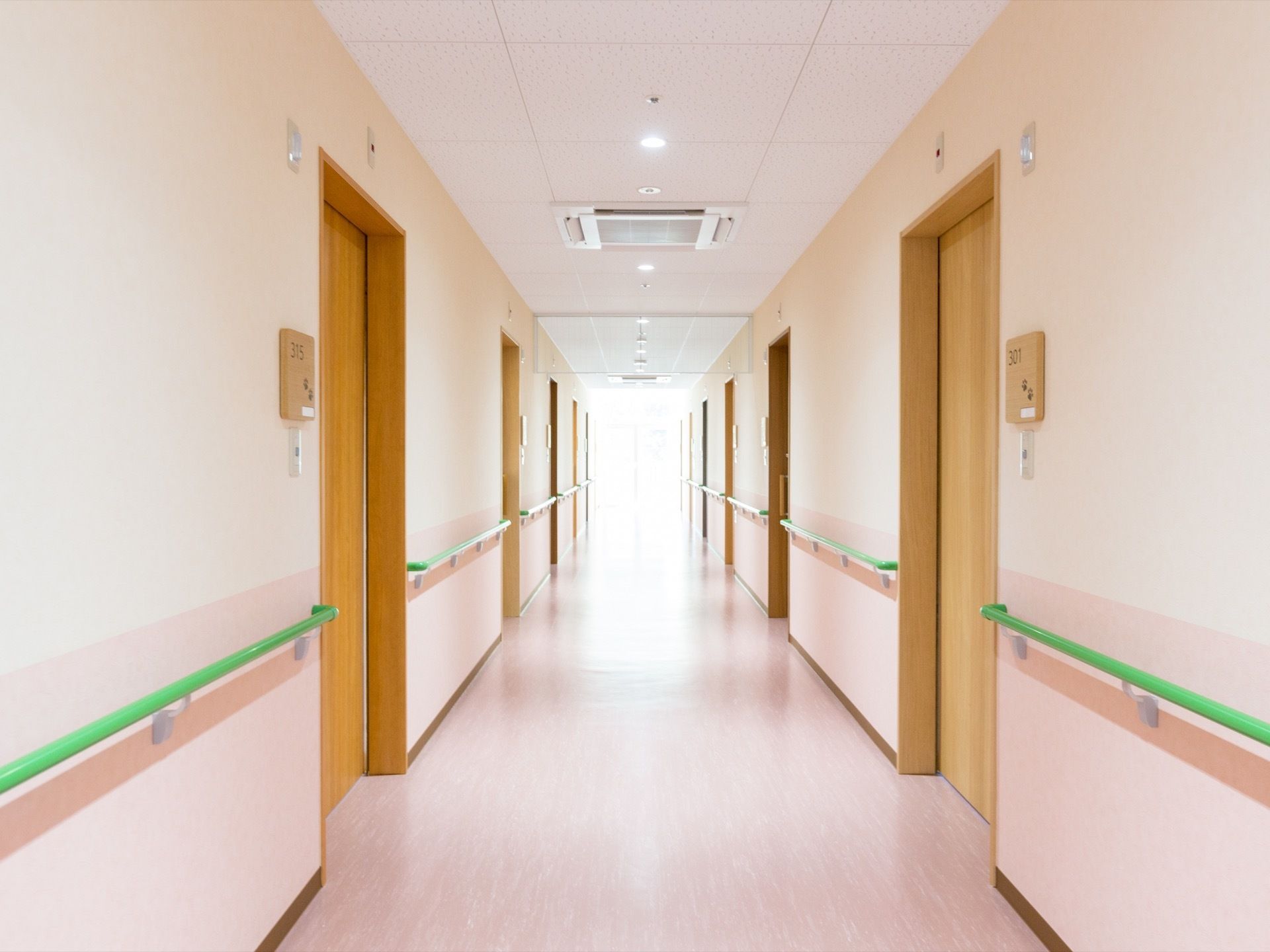 通路の奥に設置されている窓からは日の光が差し込んでいる。手すりが設けられており、壁には部屋番号が記されている。