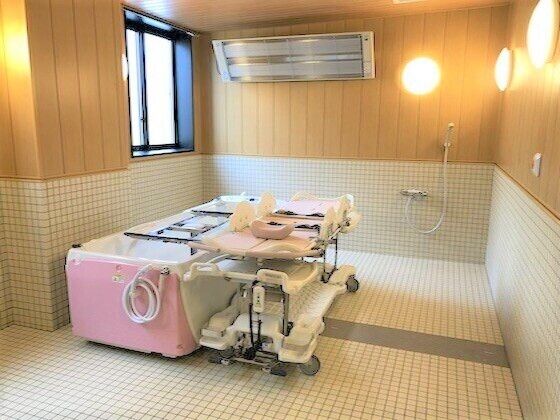 寝たまま入浴可能な寝台浴が置かれた浴室はタイル張りで大きな窓やパネルヒーター、シャワーも付いている。