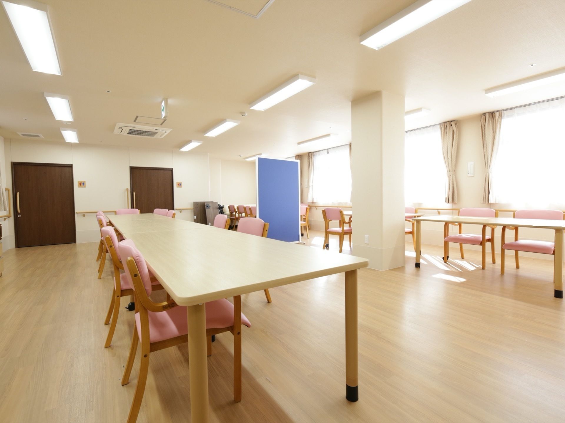 広々とした共有スペースである。木製のテーブルと椅子が整然と並べられている。窓があり、天井の照明も多いので明るい。