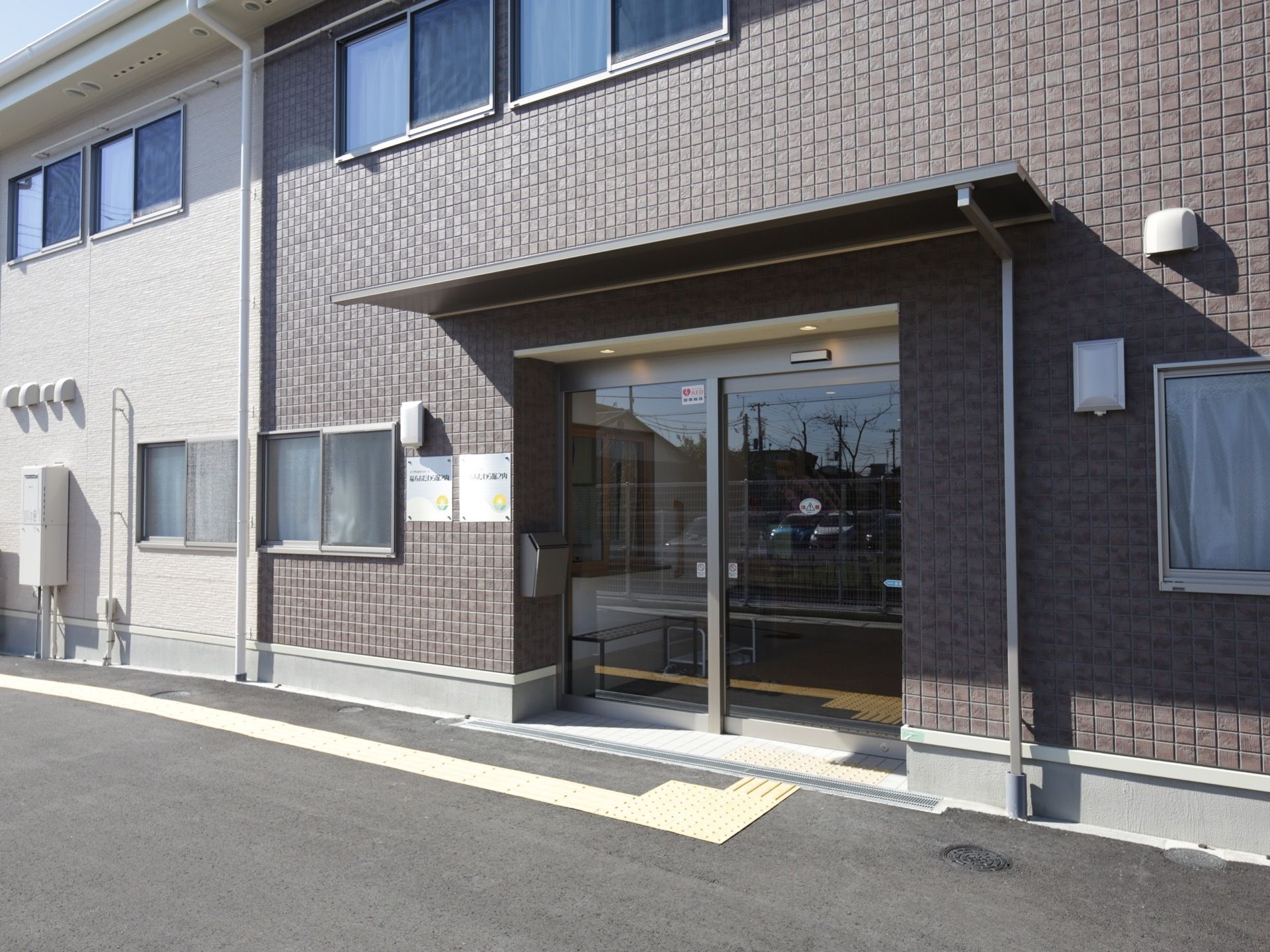 建物は白とグレーのツートンカラーの印象的な外観になっている。エントランスは自動ドアを設置してあるので、車椅子をご利用の方も出入りがしやすい。
