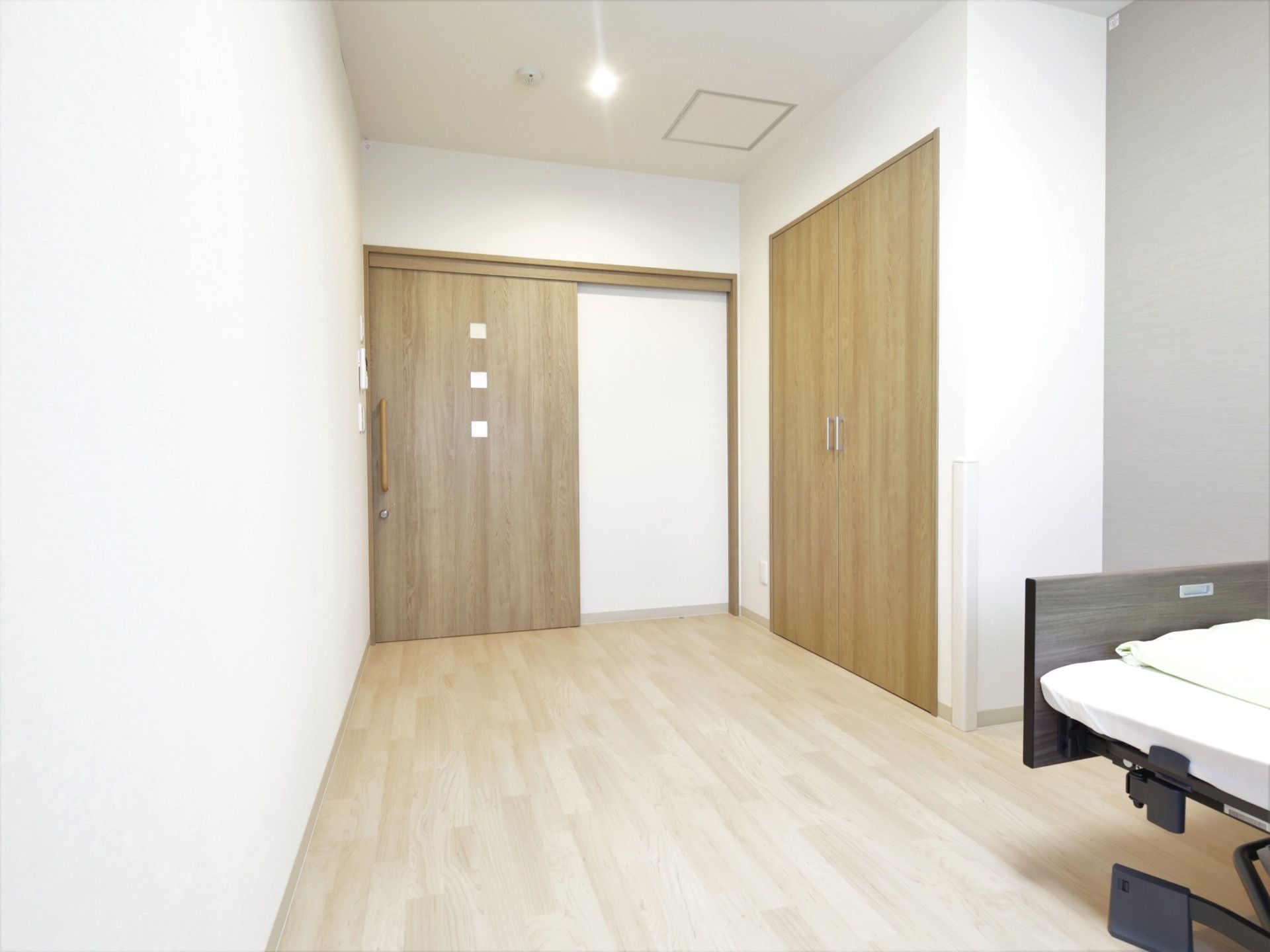 居室のドアはスライド式になっていて、間口が広く出入りがしやすい。壁には電化製品のリモコンが集約して設置されている。