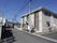 施設の建物は閑静な住宅街に建っていて、周囲には落ち着いた雰囲気がある。建物の奥には、雄大な山並みが見える。