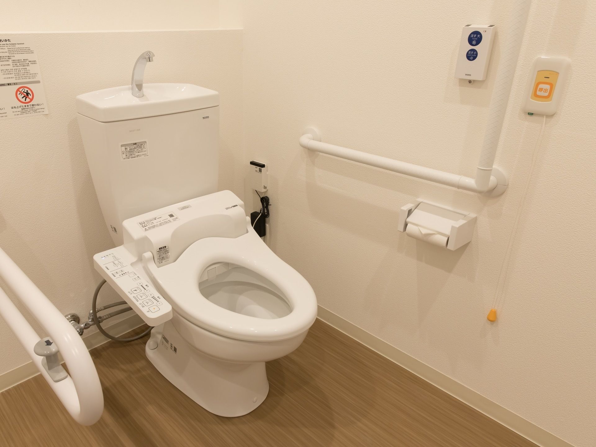 綺麗なトイレである。便器の両側に手すりが設置されている。壁に呼び出しボタンがあり、いざという時にすぐに連絡することができる。