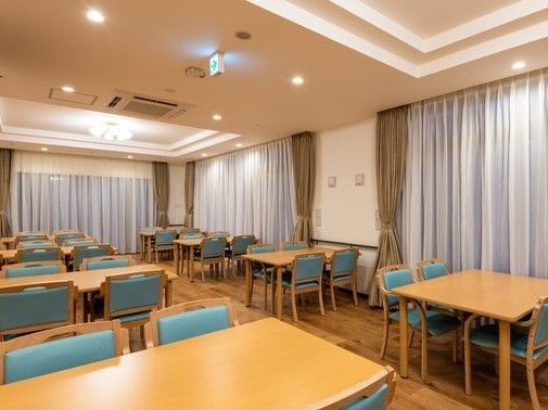 4人掛けのダイイングテーブルが複数置かれた食堂には大きな窓があり、カーテンが付いている。
