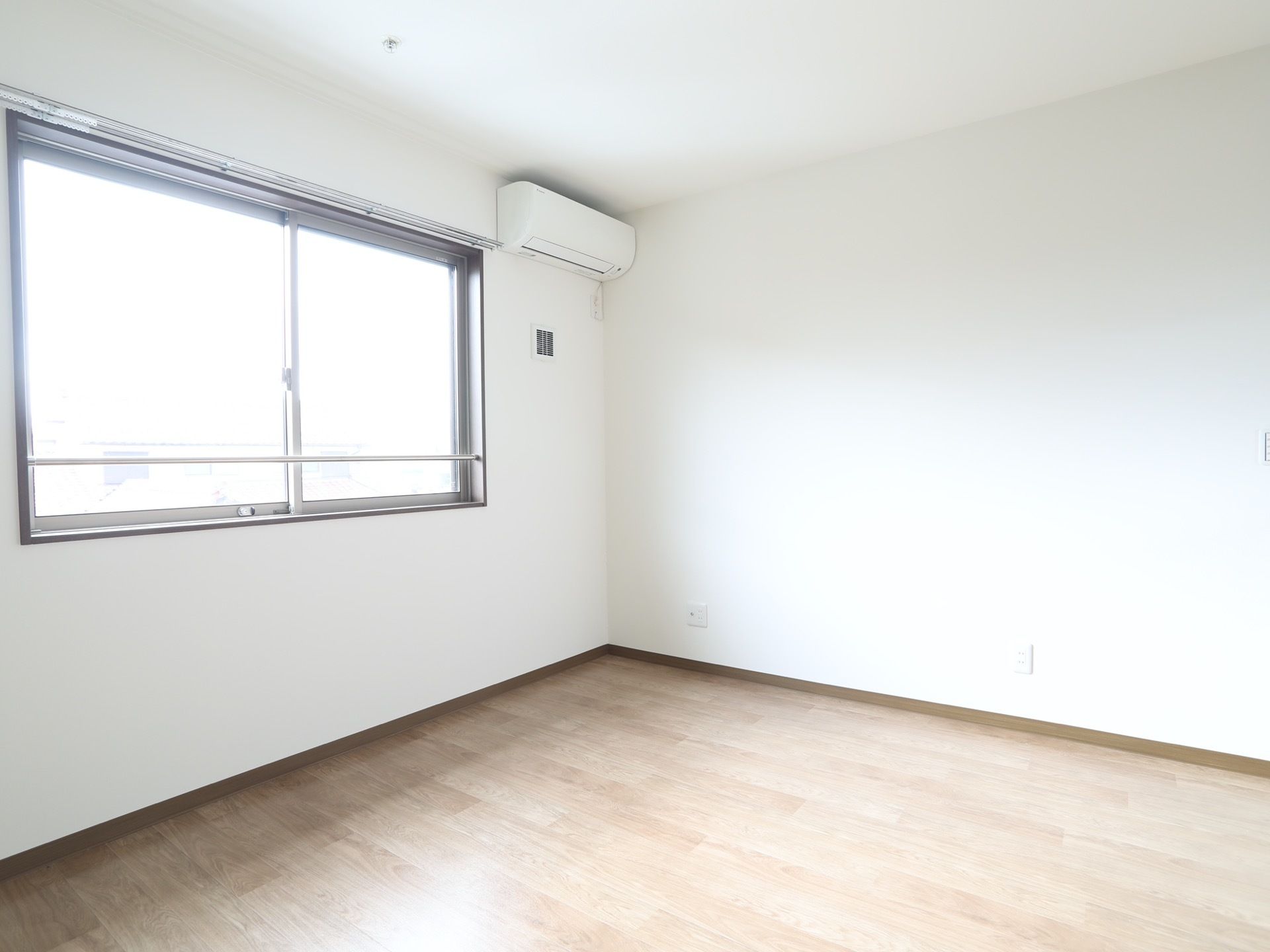 引き戸式の窓が設けられた、洋風の居室である。外の景色が見渡せる。コーナーにエアコンが設置されている。