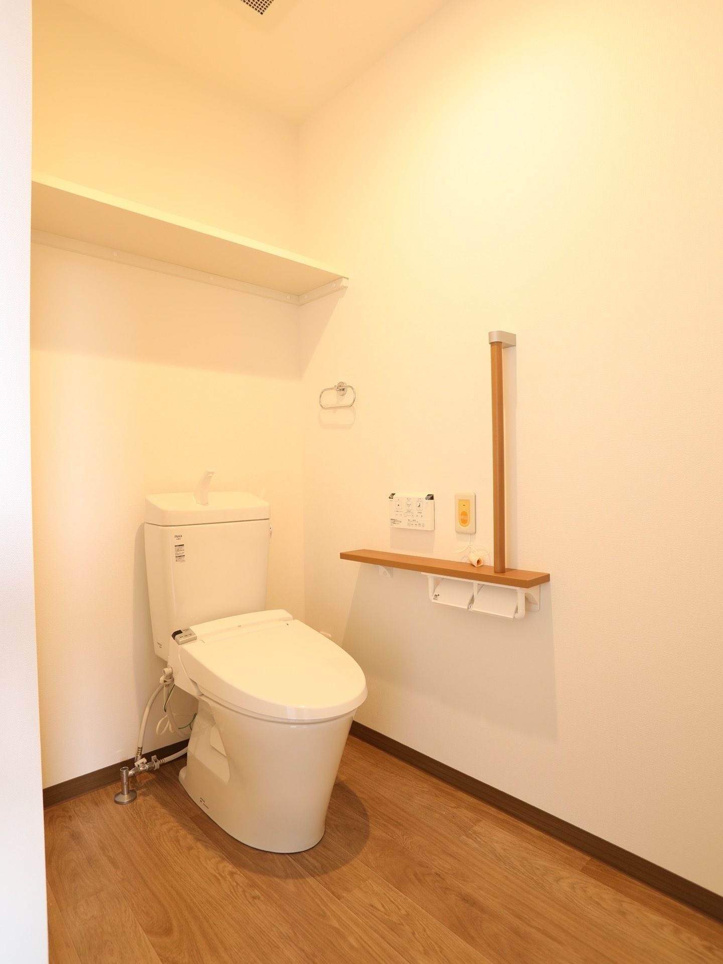 洋式便座を完備している。タンク上に手洗い場を設置。壁側にはトイレットペーパーホルダーやナースコールなどがある。