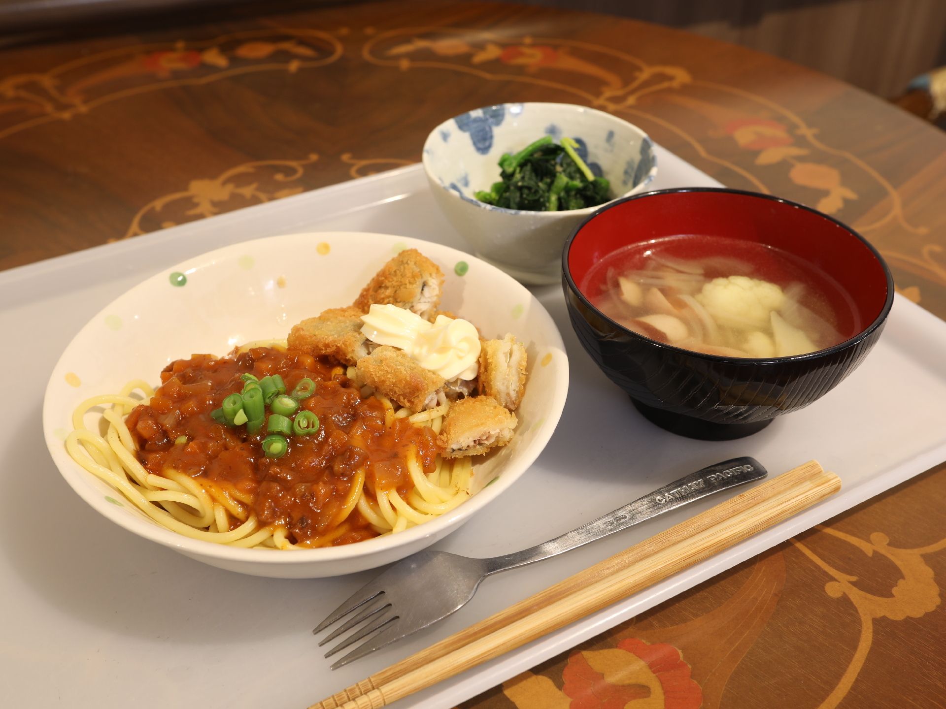 メイン料理、お椀、小鉢にお箸とフォークが添えられたお盆