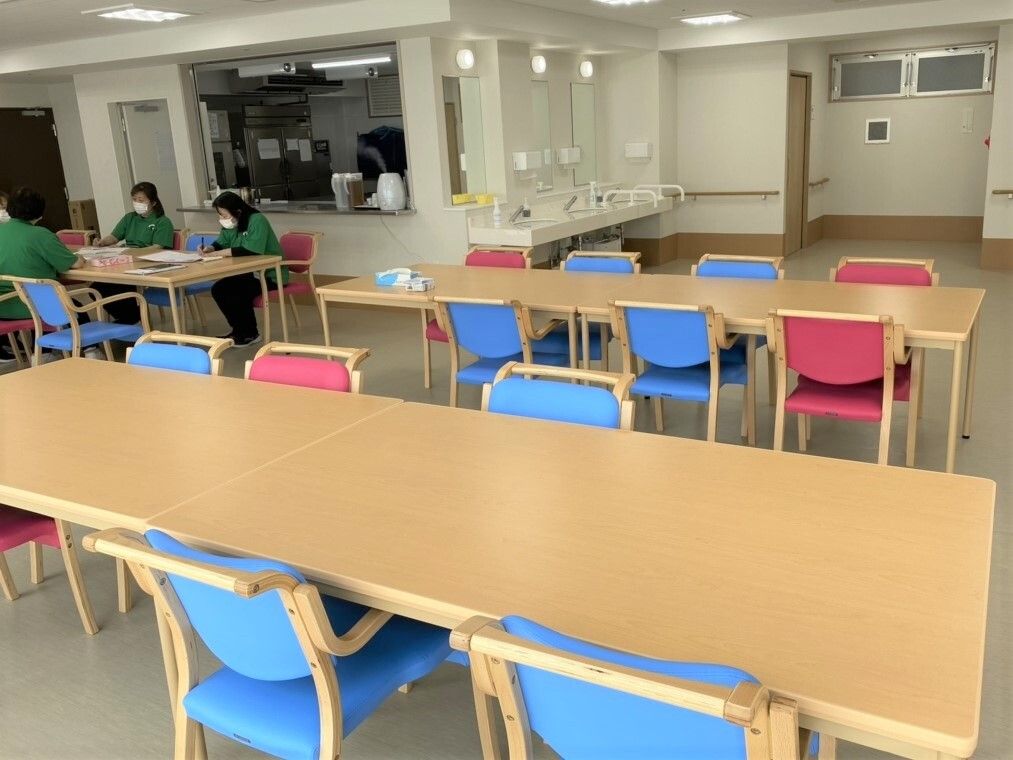 ダイニングテーブルが並んだ食堂は、落ち着いた雰囲気。奥には洗面所があり、スタッフが集まって話し合いをしているテーブルもある。