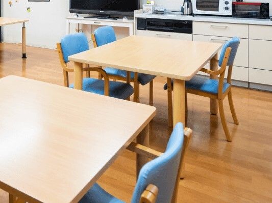 少人数のダイニングテーブルが複数置かれた共有スペース。テレビもあり、電子レンジなどの家電も置かれている。