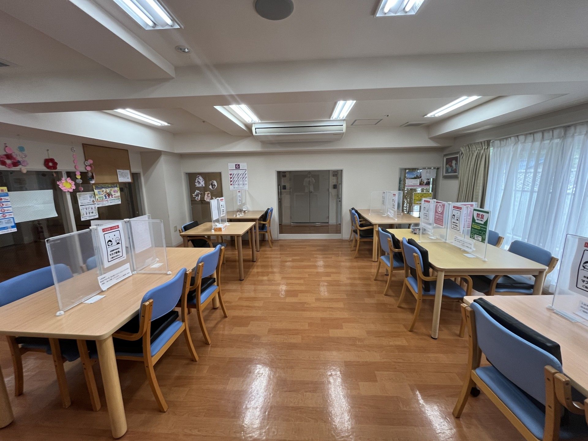 寝具付きのベッドが置かれた部屋。大きな窓が付き、いすとテーブルがある。