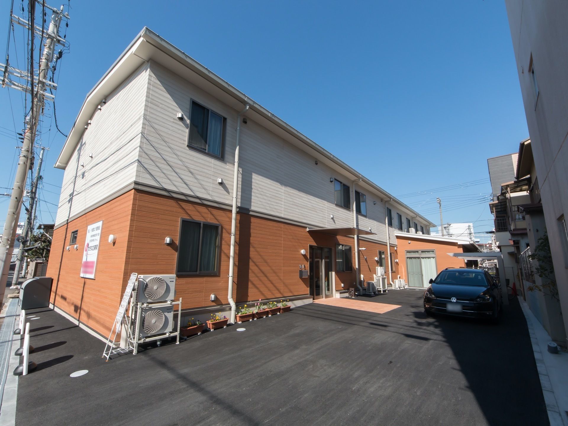 施設は幹線通り沿いに建てられた２階建ての建物である。施設の隣りには数台分の駐車スペースが設置されている。