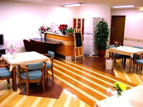フローリングの床は色分けされ、壁の色は白色基調である。テーブルや椅子が十分な間隔をあけて置かれている。