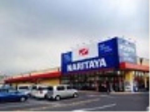 スーパーマーケットの店舗の外観である。建物は平屋建てで、入口の上には大きな看板がある。店舗の前は駐車場になっている。