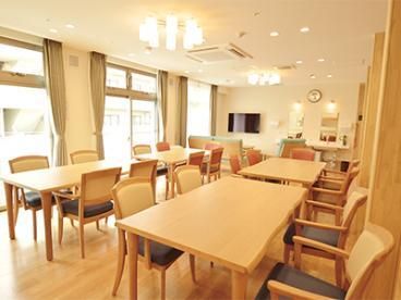 大きな壁掛けテレビが設置されているリビングダイニングには木製のテーブルセットが複数置かれている。