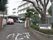 奥に施設の玄関が見える。玄関前に車が２台停まっている。レンガ造りの門柱があり、その間に白い門扉が畳まれている。右側に施設名の看板がある。