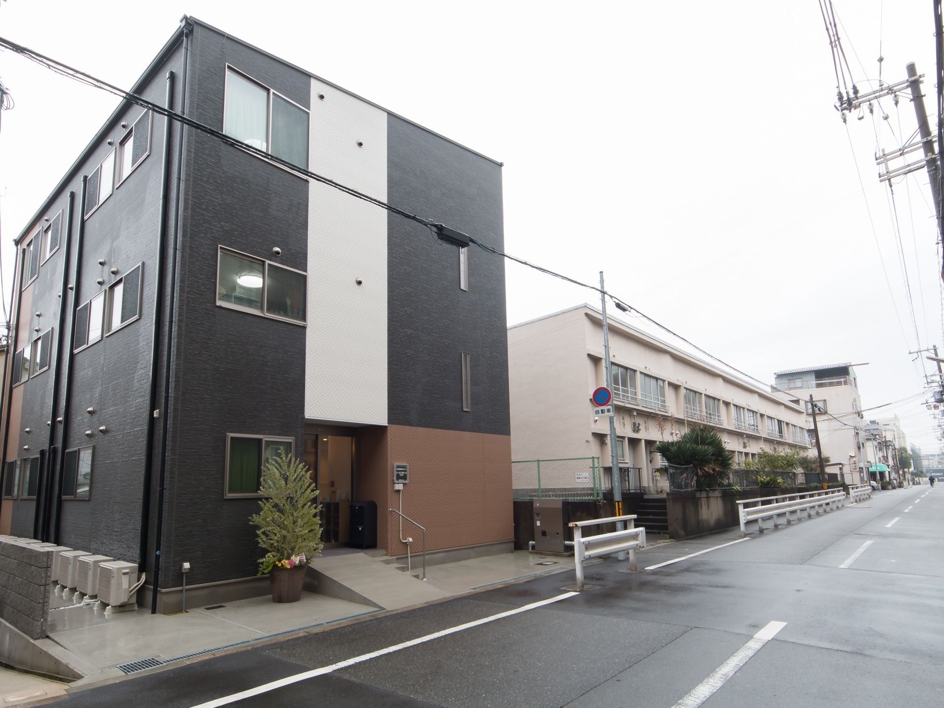 黒を基調とした、スタイリッシュな３階建ての施設である。出入口はガラス張りの自動ドアになっており、観葉植物が飾られている。