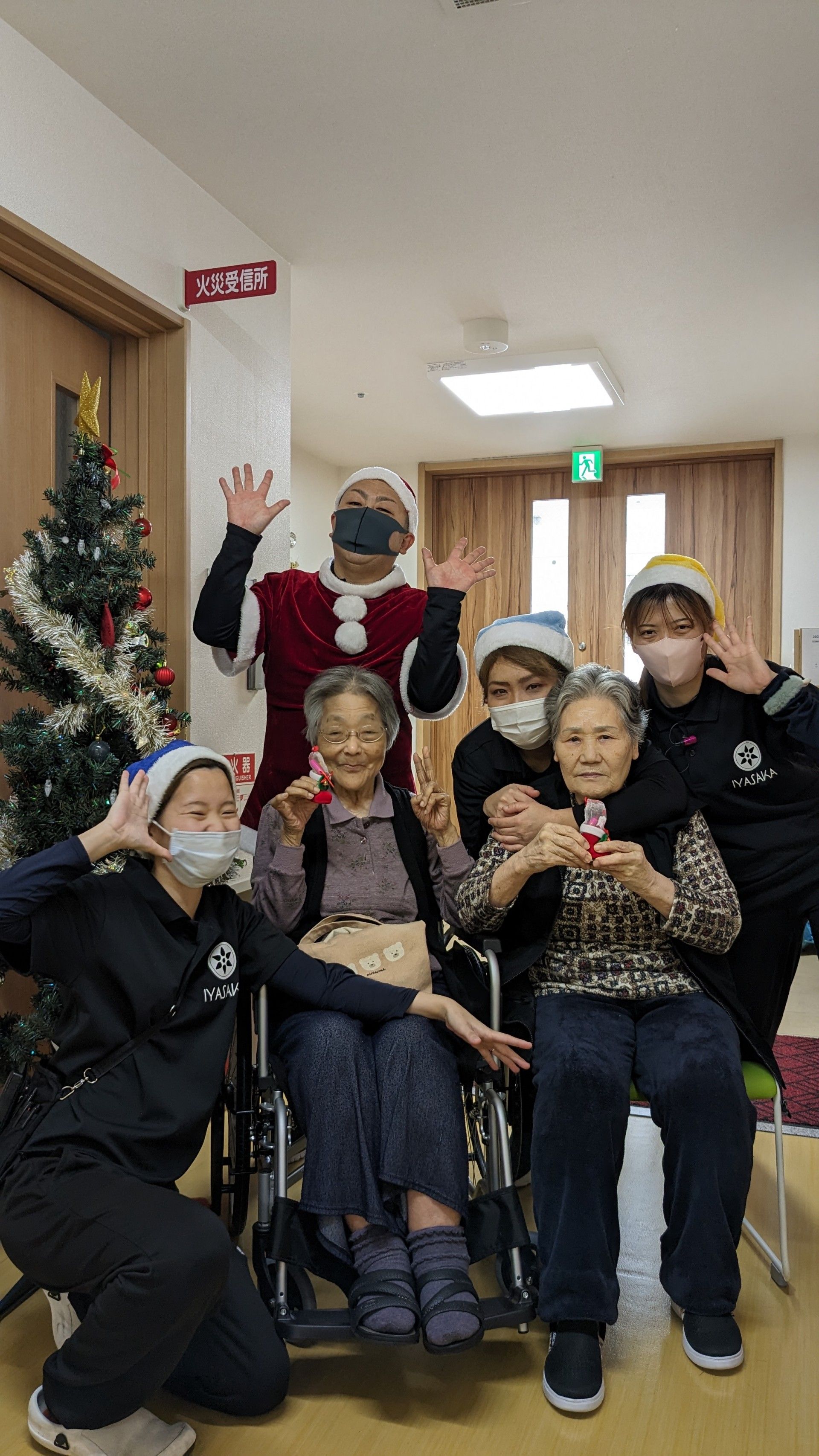 高齢者の方にタオルをかけてマッサージしているスタッフと振り返りながら会話する女性の様子