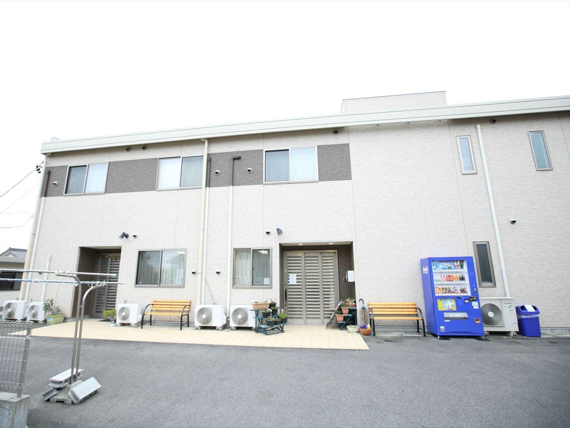 施設はベージュを基調とした2階建ての建物である。出入り口のドアが正面と左側にあり、右側には自動販売機が設置されている。