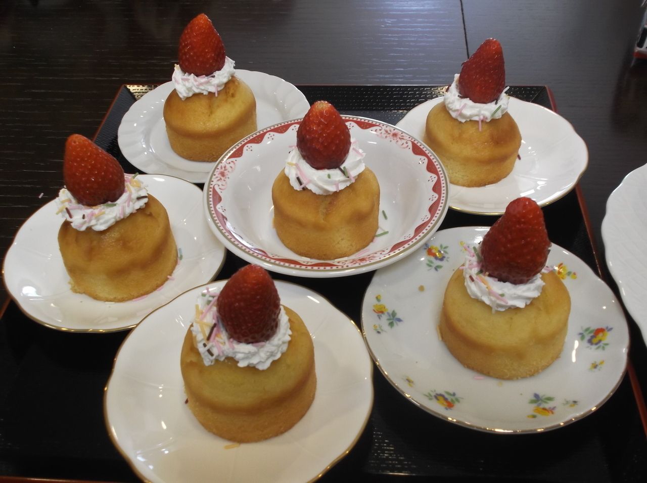 小皿に盛り付けられた生クリームと苺をトッピングしたケーキ
