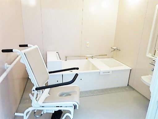 浴室用の車いすがセットされた浴室には一人用の個浴があり、手すりや呼び出しボタンもついている。