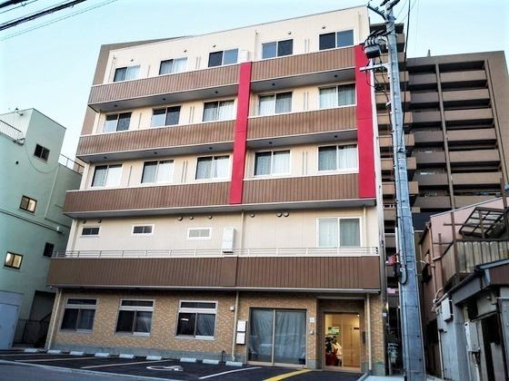 5階建ての建物の各フロアにはベランダが付き、建物の前には駐車場がある。